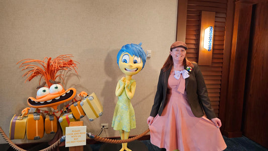 Kelly bounding as Bing Bong next to statues of Joy and Anxiety at Pixar Place in Disneyland