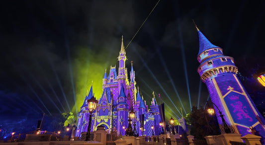 Cinderella Castle lit up with a purple theme at Magic Kingdom