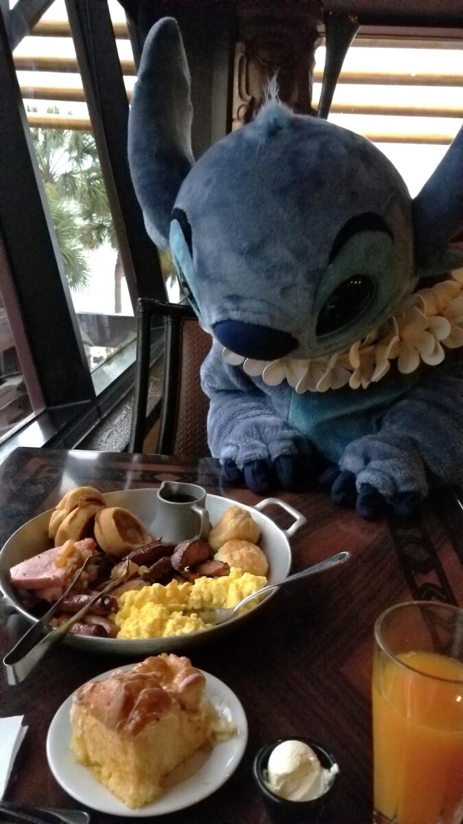 Stitch looking at the breakfast food options on my table at ‘Ohana restaurant