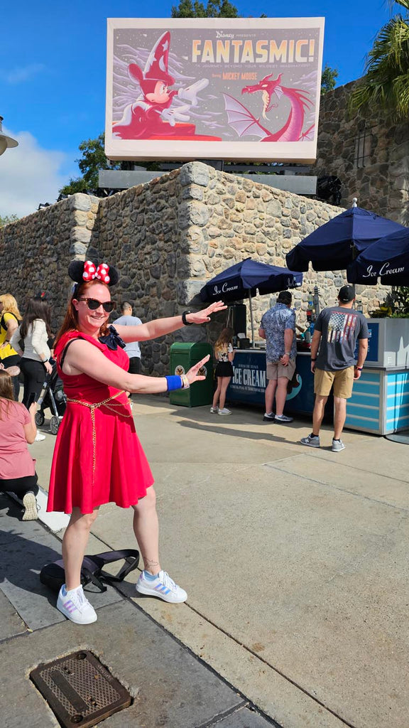 Kelly bounding as Sorcerer Mickey while standing in front of a Fantasmic poster at Disney’s Hollywood Studios
