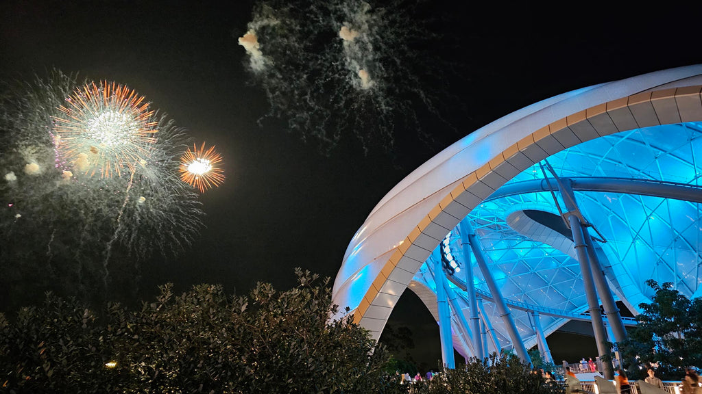 walkway to Tron with fireworks going off in the distance at the Magic Kingdom