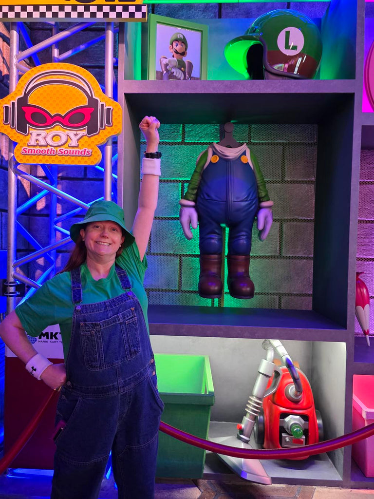 Kelly bounding as Luigi in front of the race gear at Mario Kart: Bowser's Challenge