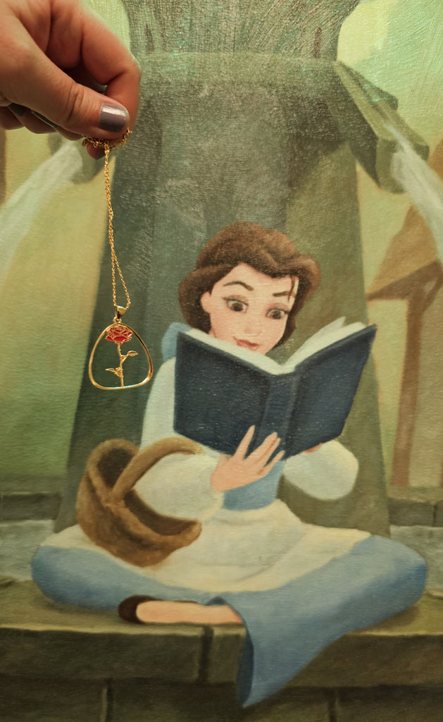 Red rose necklace in front of a photo of Belle from Beauty and the Beast