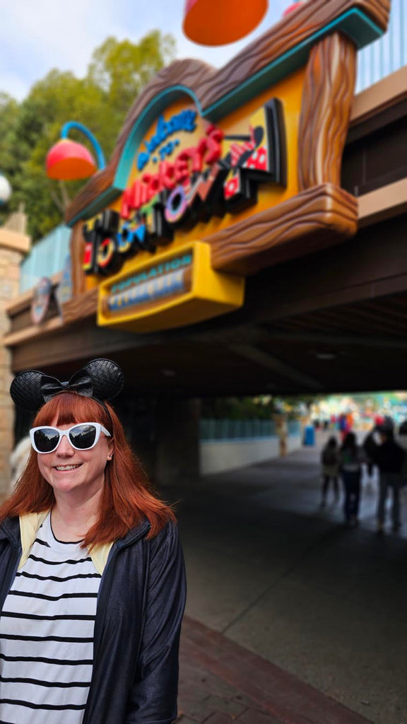 Kelly bounding as Mickey Mouse in front of the Toontown sign