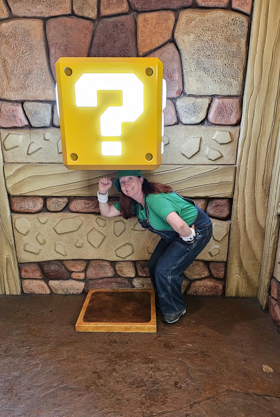 Kelly bounding as Luigi hitting a question block in Super Nintendo World