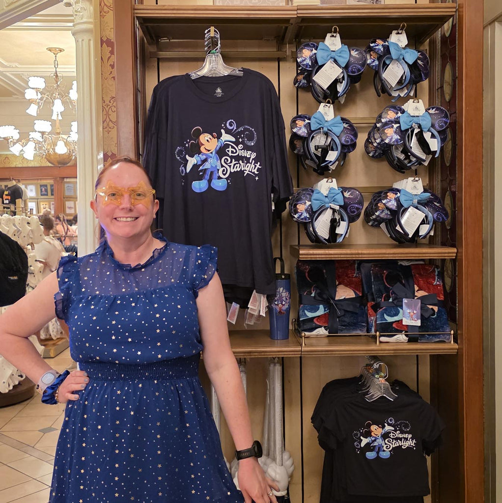 Kelly bounding as the Blue Fairy standing in front of Disney Starlight parade merchandise