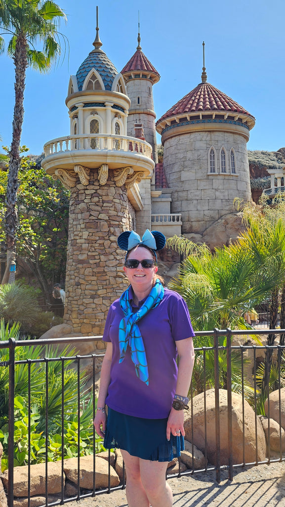Kelly bounding as Ariel in front of the Journey of the Little Mermaid attraction at Magic Kingdom