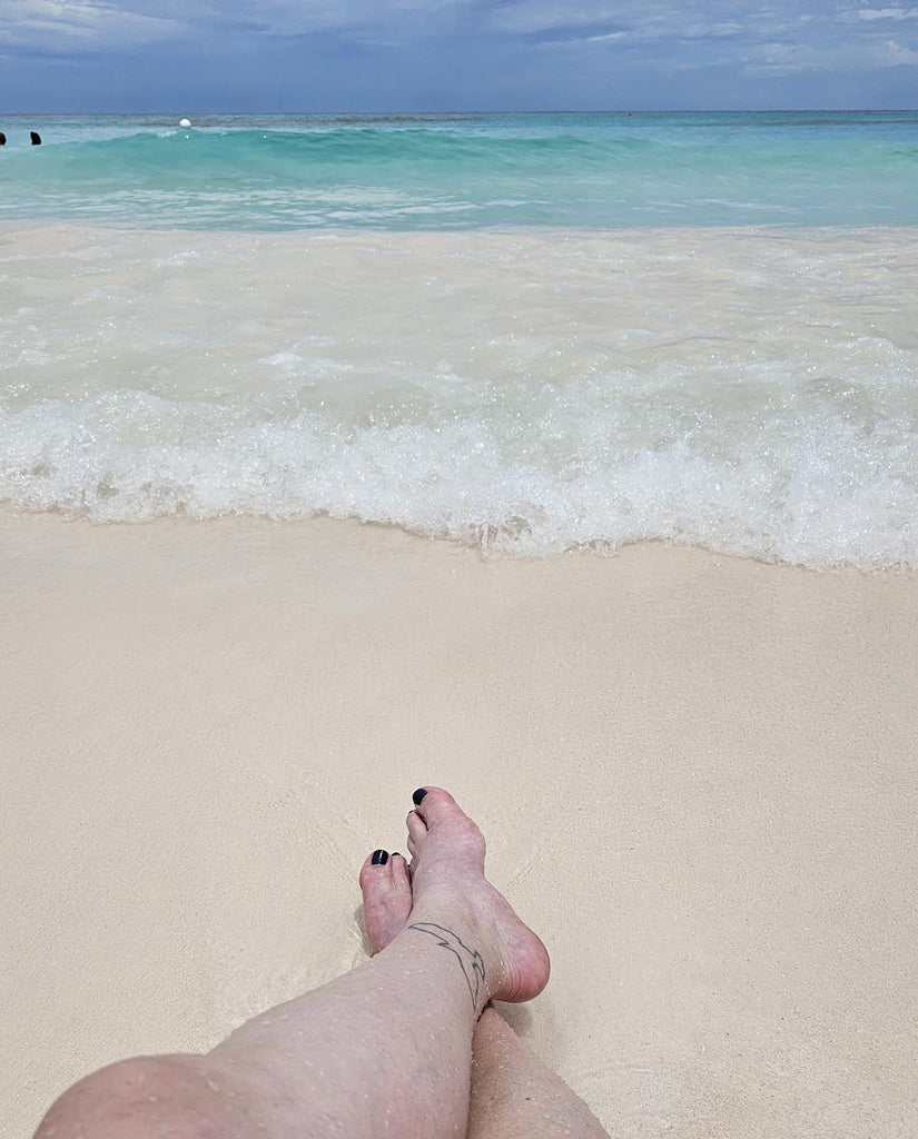 Kelly legs lounging at the waterline on the beach at Lookout Cay at Lighthouse Point