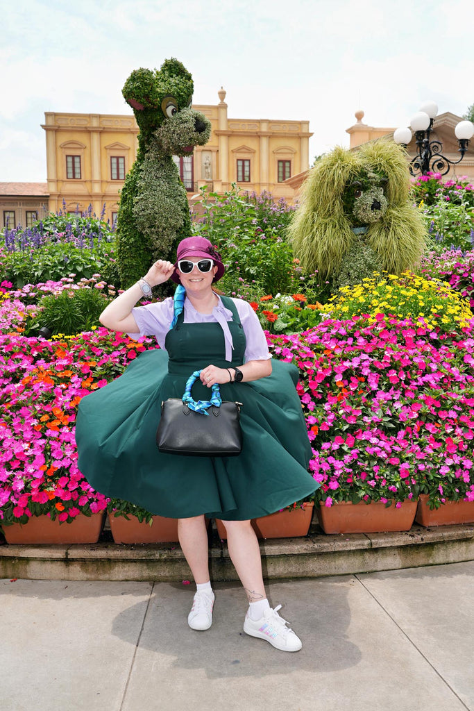 Kelly in her Dapper Ariel bound at Epcot standing in front of a Lady and the Tramp topiary