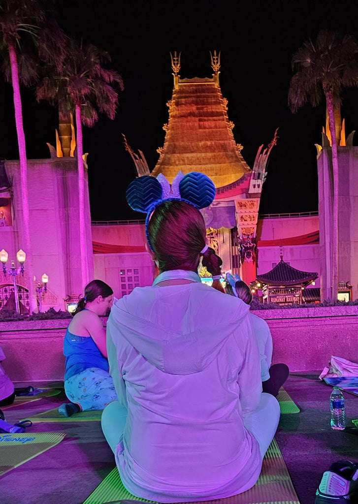 Kelly sitting on a yoga mat in front of the Grauman Chinese Theatre for Early Morning Yoga at Disney’s Hollywood Studios