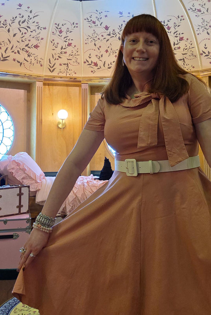 Kelly bounding as Glinda in front of the set of Shiz University bedroom for Wicked at Universal Studios Orlando