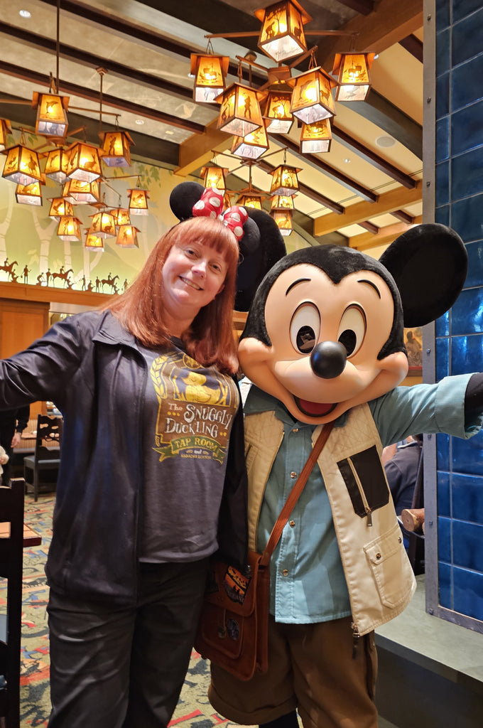 Kelly posing for a photo with Mickey Mouse at Storytellers Café