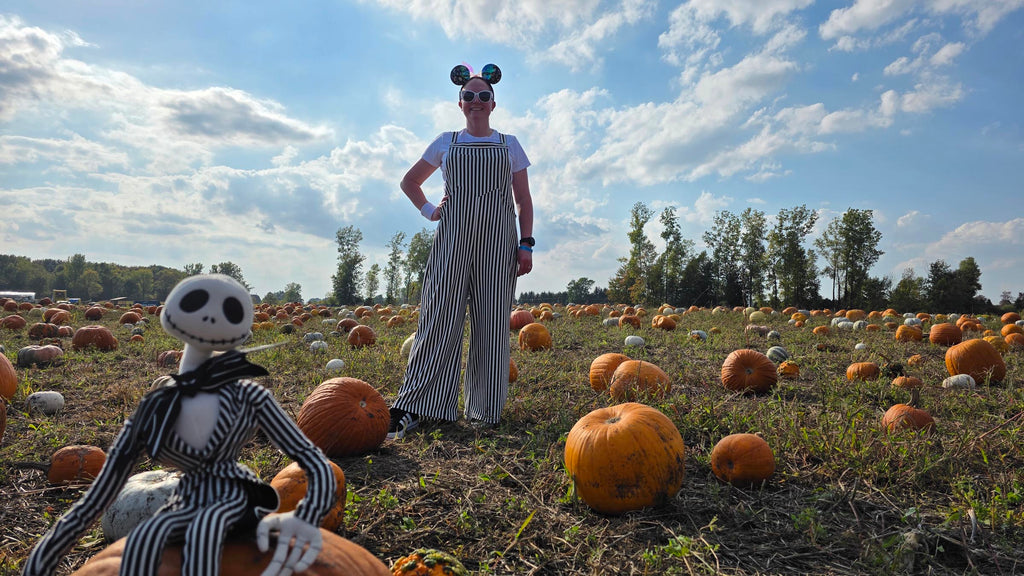 Kelly bounding as Jack in a pumpkin patch with a Jack Skellington figurine in the forefront of the image