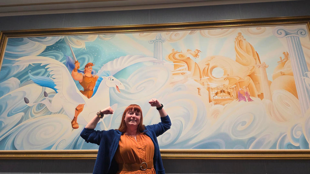 Kelly bounding as Hercules in front of a Hercules mural on the Disney Destiny