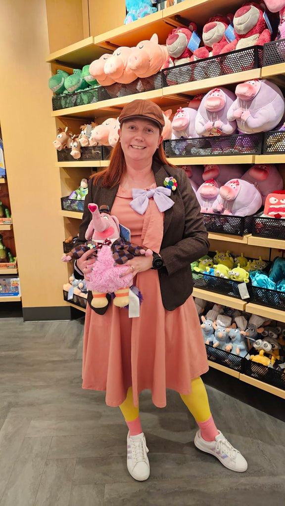 Kelly bounding as Bing Bong at Disney California Adventure while holding a stuffed animal Bing Bong