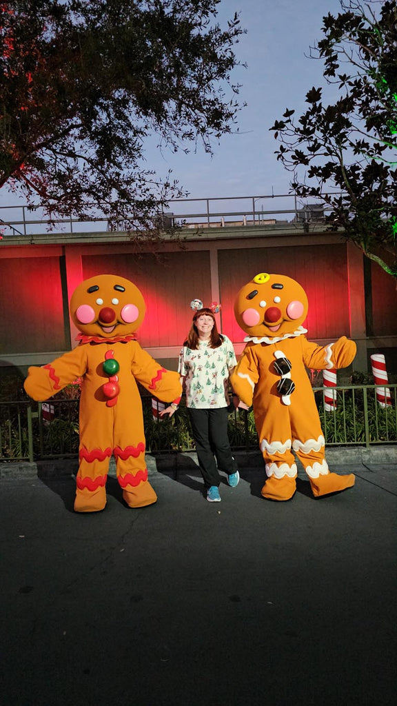Kelly posing for a photo with gingerbread characters at Mickey’s Very Merry Christmas Party