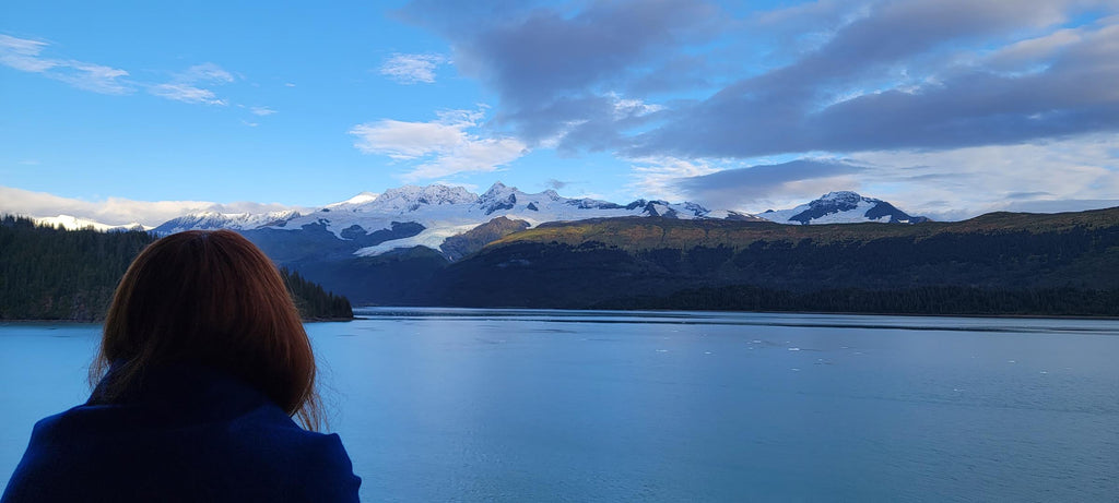 Kelly standing on a ship’s balcony watching the world sail by