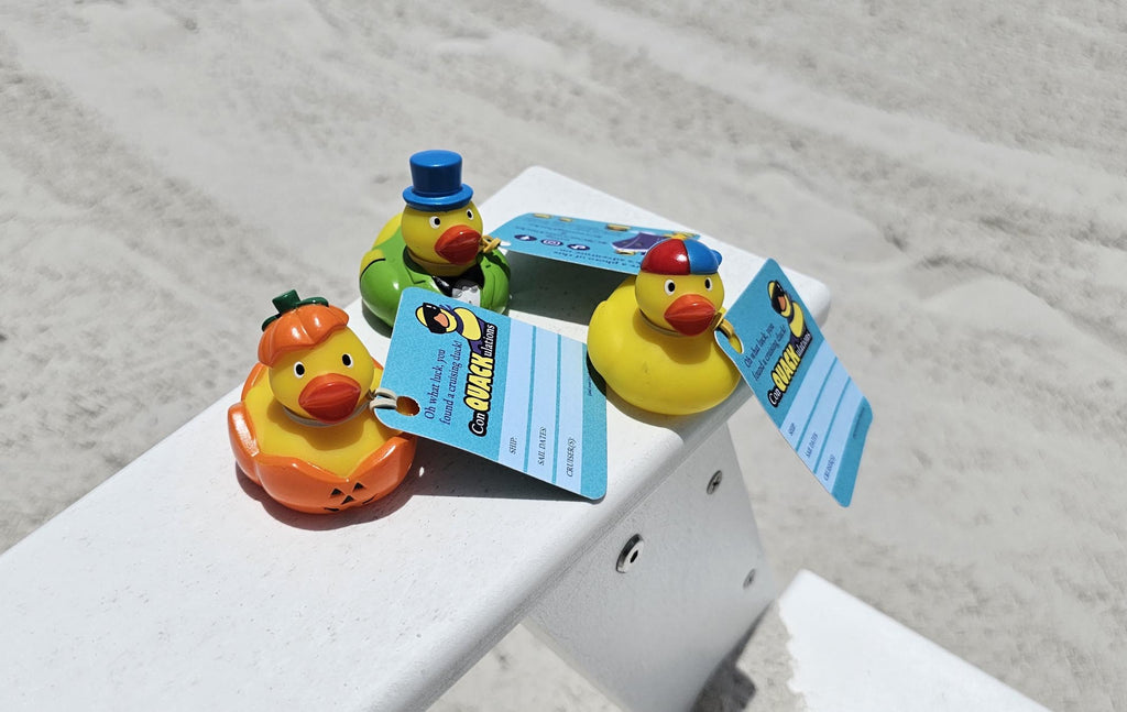 3 rubber ducks with tags sitting on the arms of a white loungchair